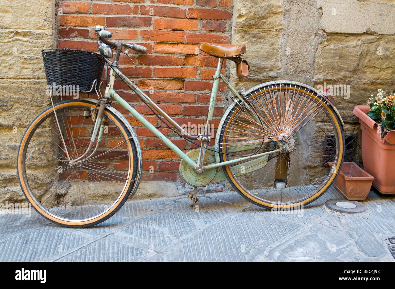 Bicicletta Legnano d'epoca con cesto di vimini parcheggiato contro un vecchio muro di mattoni e pietra in un pittoresco vicolo italiano Foto Stock