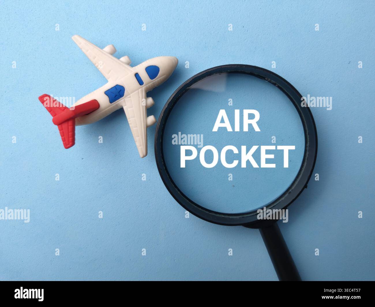 Lente d'ingrandimento che mette a fuoco le parole AIR POCKET con aeroplano giocattolo su sfondo blu. Foto Stock