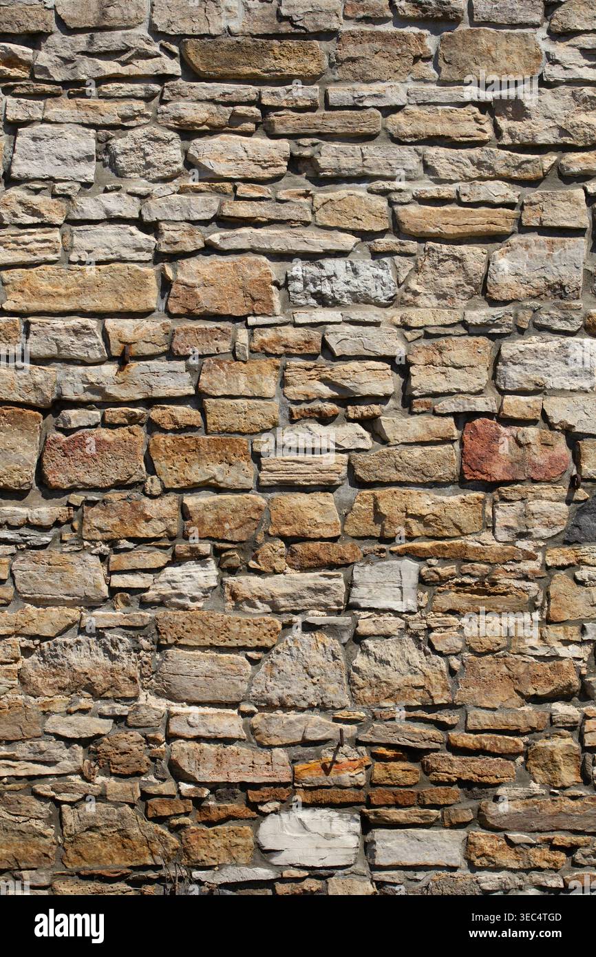 Pareti in pietra ruvida con varie dimensioni e sfumature naturali. Le pietre formano una superficie robusta e resistente agli agenti atmosferici. Le texture mostrano l'età e la maestria artigianale. Ideale per gli architetti Foto Stock