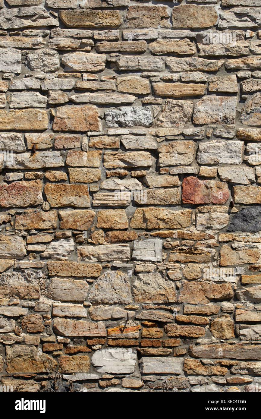 Pareti in pietra ruvida con varie dimensioni e sfumature naturali. Le pietre formano una superficie robusta e resistente agli agenti atmosferici. Le texture mostrano l'età e la maestria artigianale. Ideale per gli architetti Foto Stock