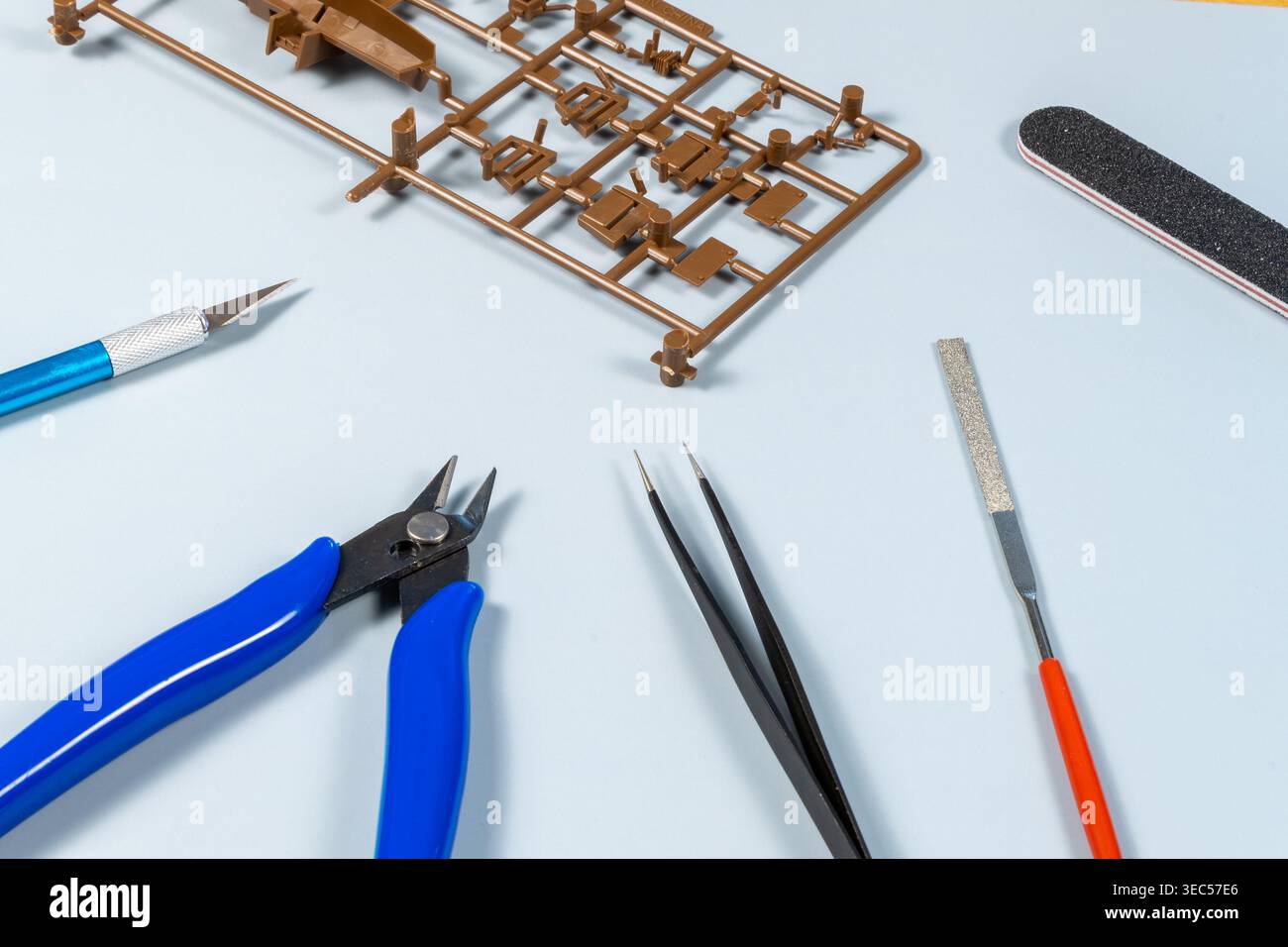 Disposizione piatta di strumenti di modellazione in plastica con pinze, lima, pinzette e aerografo sulla superficie di lavoro Foto Stock