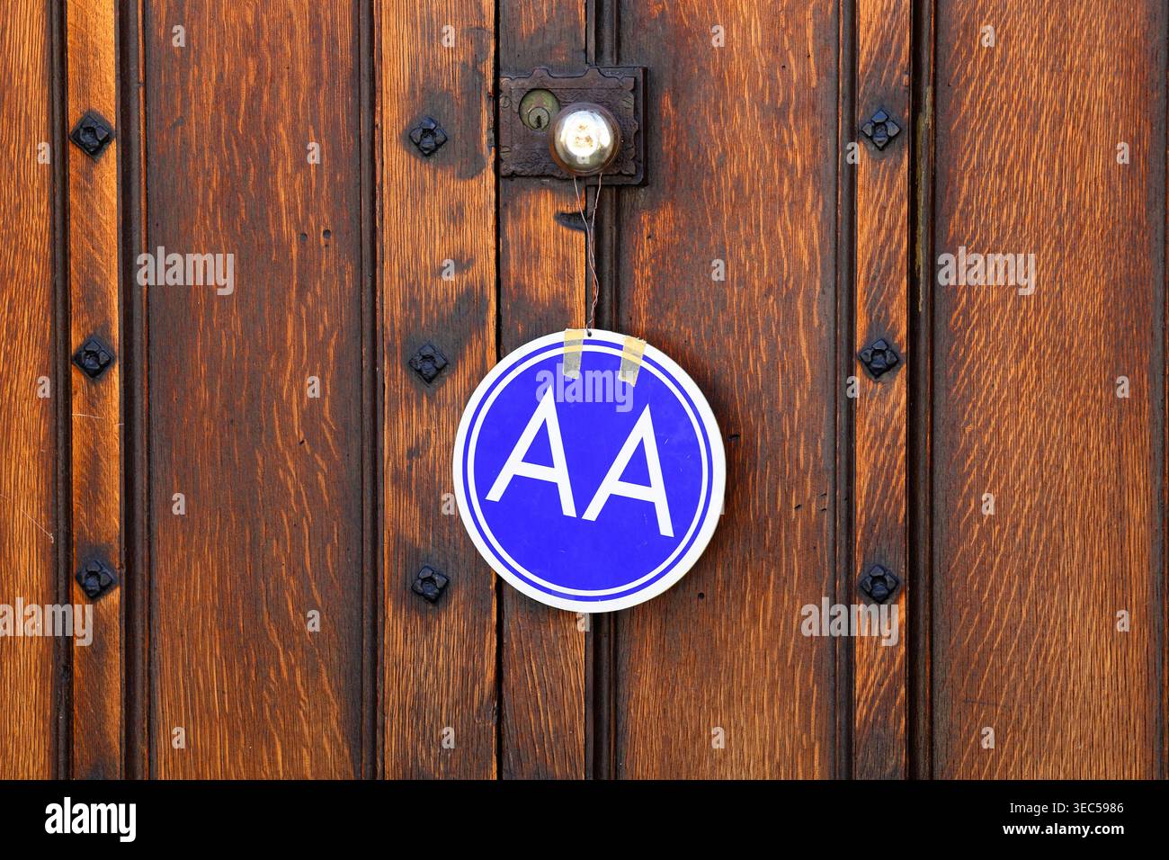 Un cartello di riunione Alcolisti anonimi appeso su un pomello di una porta di legno elegante. Foto Stock