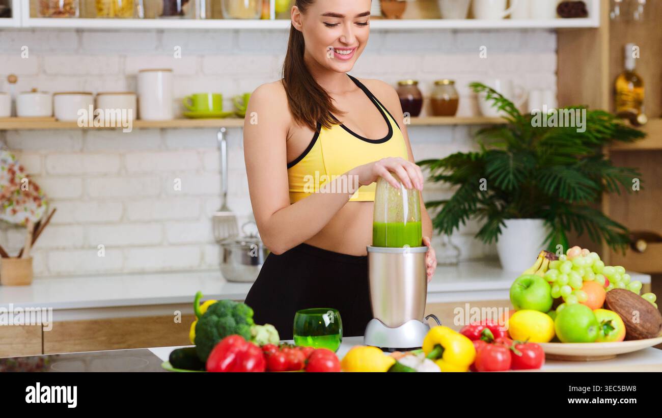 Donna mescola la bevanda sana in cucina con frutta e verdura fresche per pasti nutrienti Foto Stock