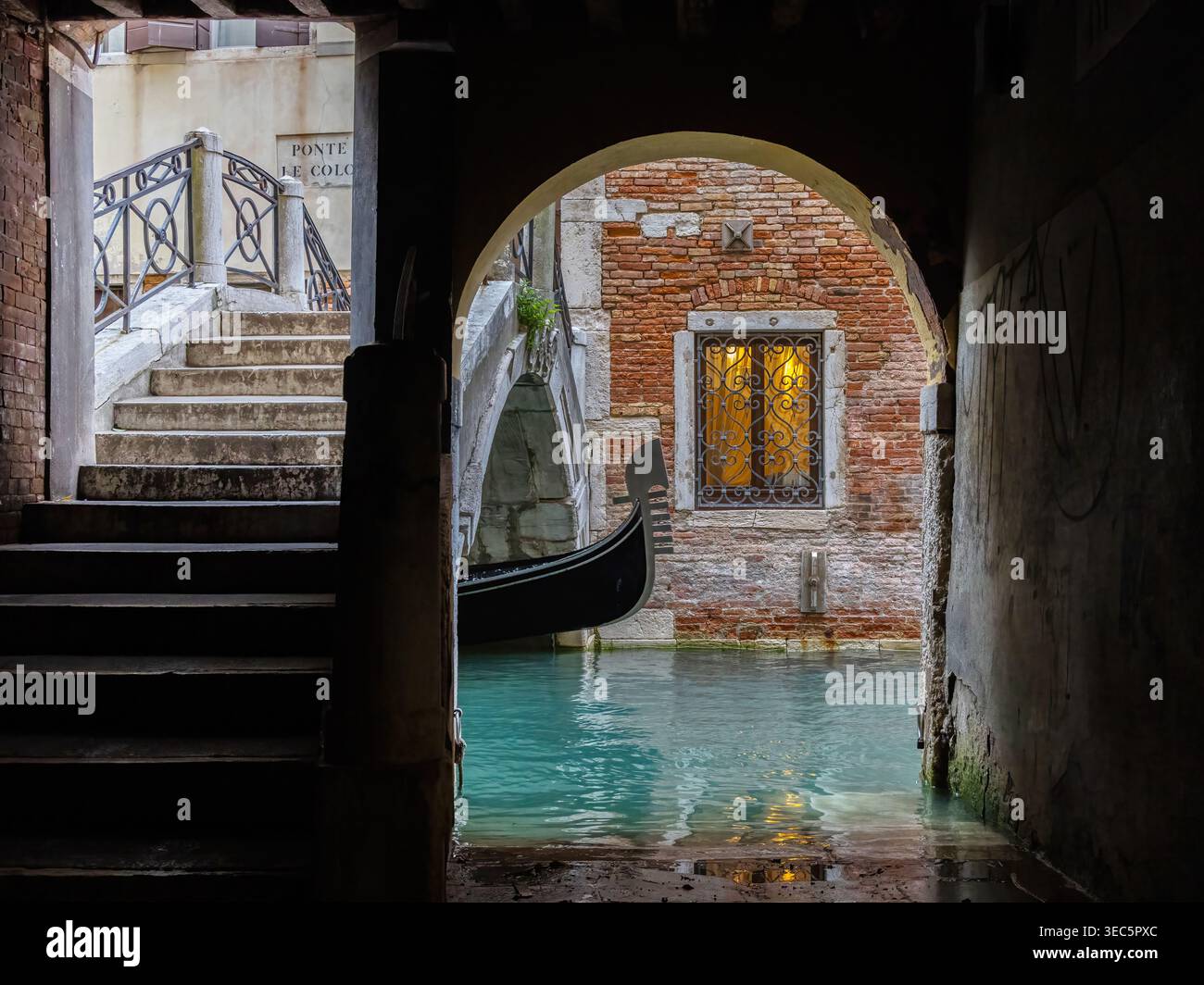 Venezia, Italia, gondola tradizionale che passa sotto un ponte storico su un canale veneziano stretto, una scena classica della famosa città lagunare. Foto Stock