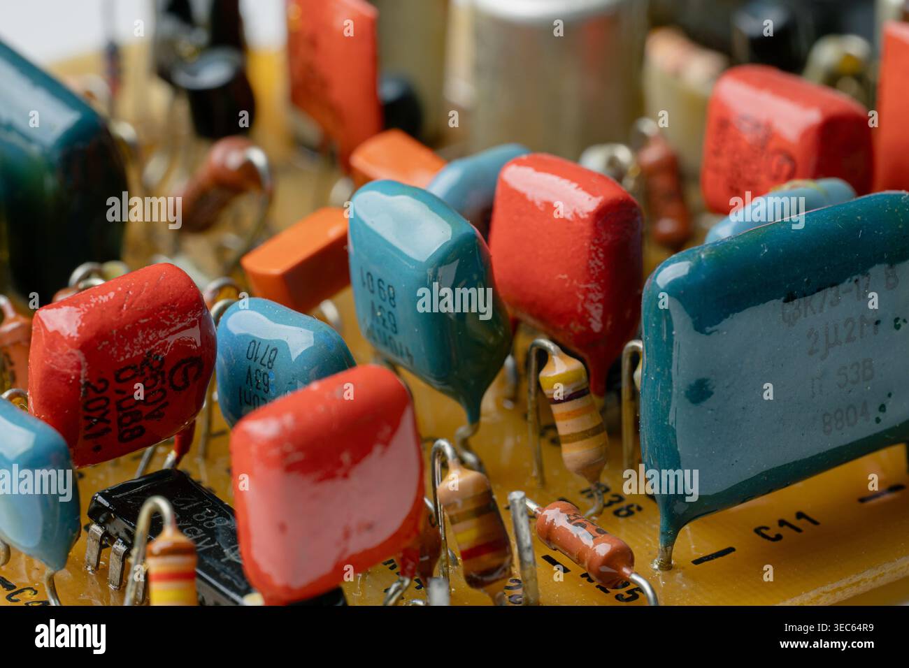 Primo piano di una scheda a circuito stampato vintage con vari resistori e condensatori colorati. Architettura hardware retrò elettronica. Vista interna dettagliata di Foto Stock