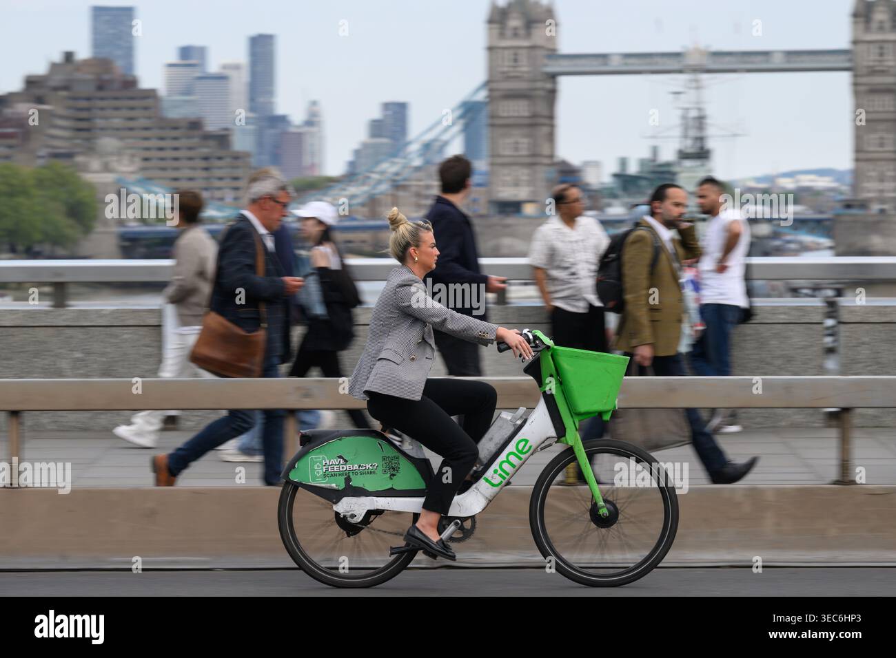 Una donna che viaggia su una bicicletta elettrica Lime attraverso il London Bridge durante l'ora di punta serale. London Bridge, Londra, Regno Unito. 27 aprile 2026 Foto Stock