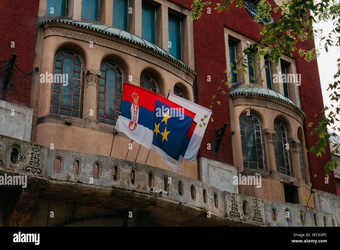 Le bandiere serbe e regionali sono appese dal balcone del municipio di Subotica, in Serbia. Identità civica, architettura istituzionale, pubblico Foto Stock