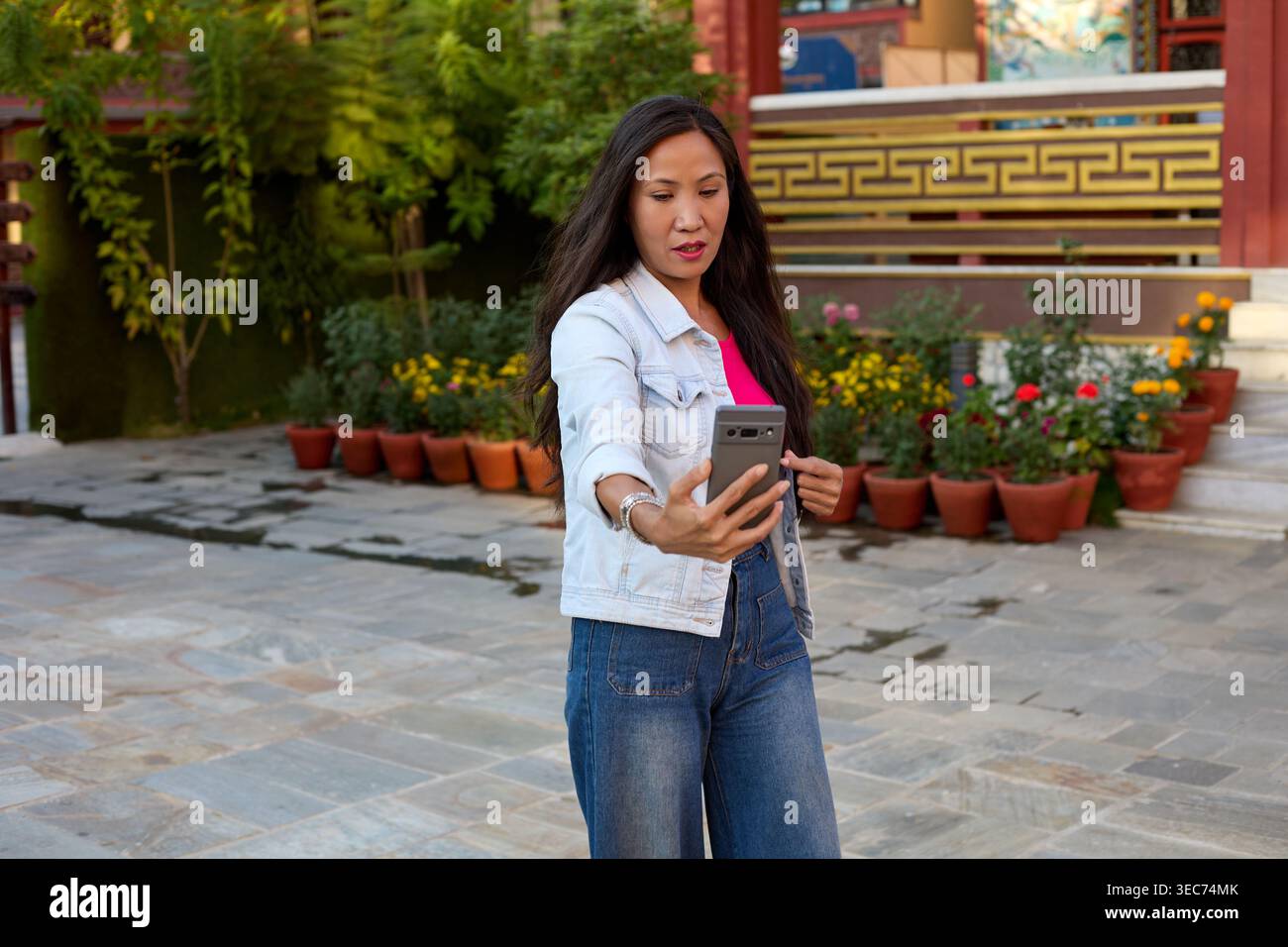 Visitatore femminile in piedi con telefono vicino all'ingresso del tempio Foto Stock