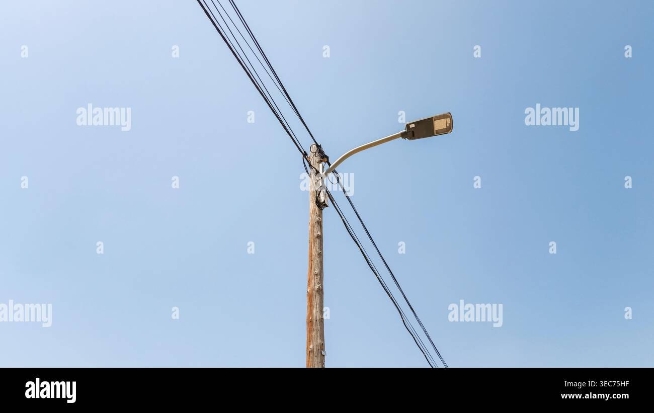Lampione invecchiato con cavi sospesi sotto Clear Blue Sky Foto Stock