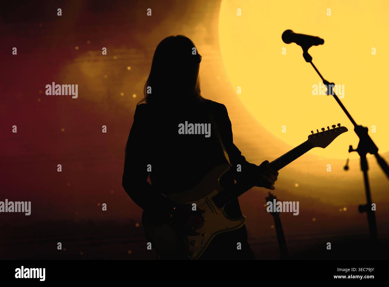 Un artista musicale si erge su uno sfondo lunare luminoso con un supporto per microfono sul palco. Foto Stock