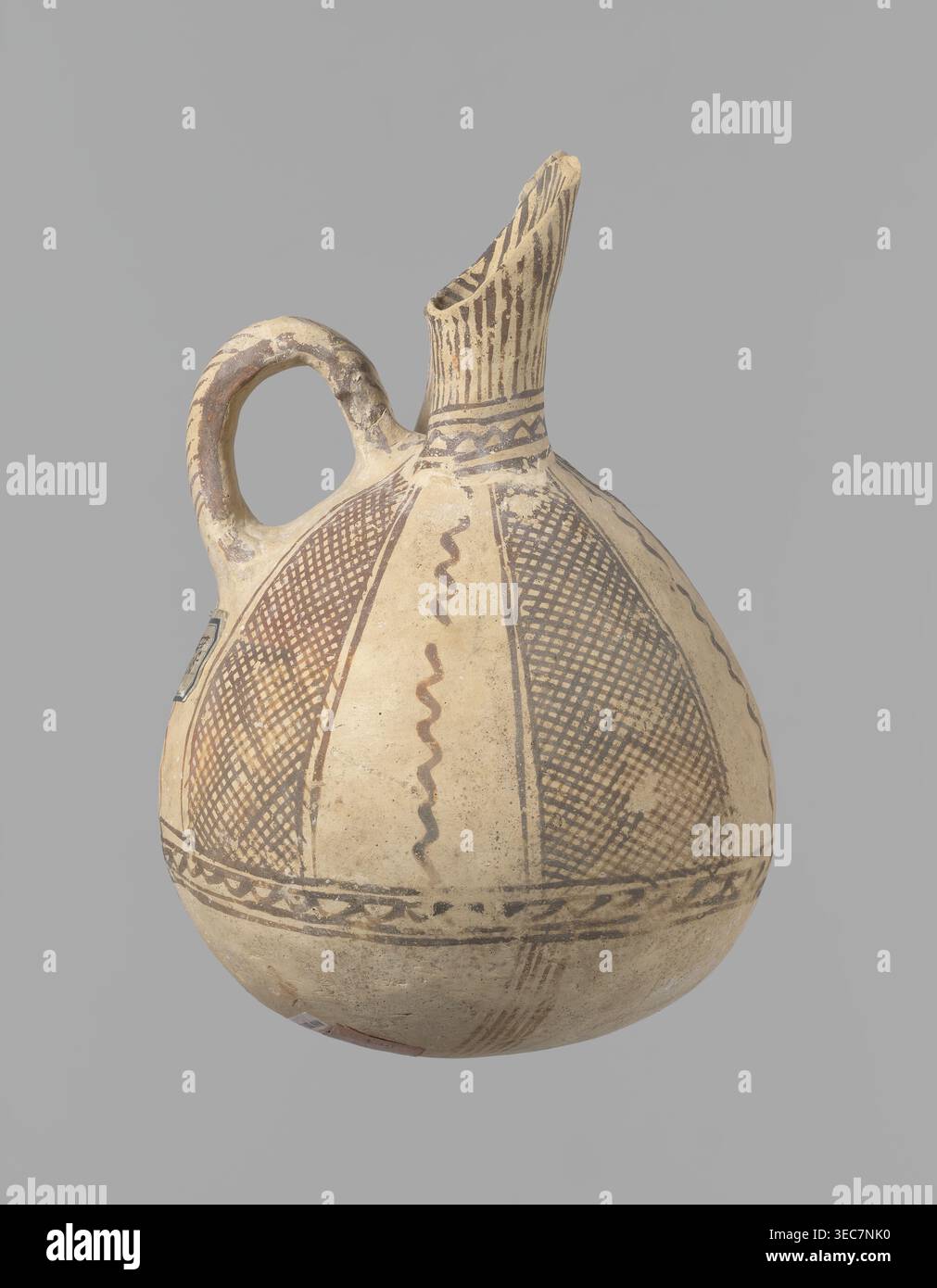 Caraffa, laboratorio cipriota sconosciuto. Caraffa bianca verniciata con fondo sferico, corpo sporgente a forma di pera che si trasforma nella parte superiore in due beccucci tubolari con pareti sporgenti. Tra di loro, una morsa ad anello sporge dal corpo. La nave è ricoperta di vernice bianca e decorata con vernice marrone-rossa. Un ornamento a zigzag corre intorno al corpo per 1/3 dell'altezza della nave, fiancheggiato su ciascun lato da due linee orizzontali. Di seguito sono riportate quattro bande di linee che convergono in basso. La parte superiore del corpo è decorata con quattro strisce piene di linee diagonali intersecanti; la Foto Stock