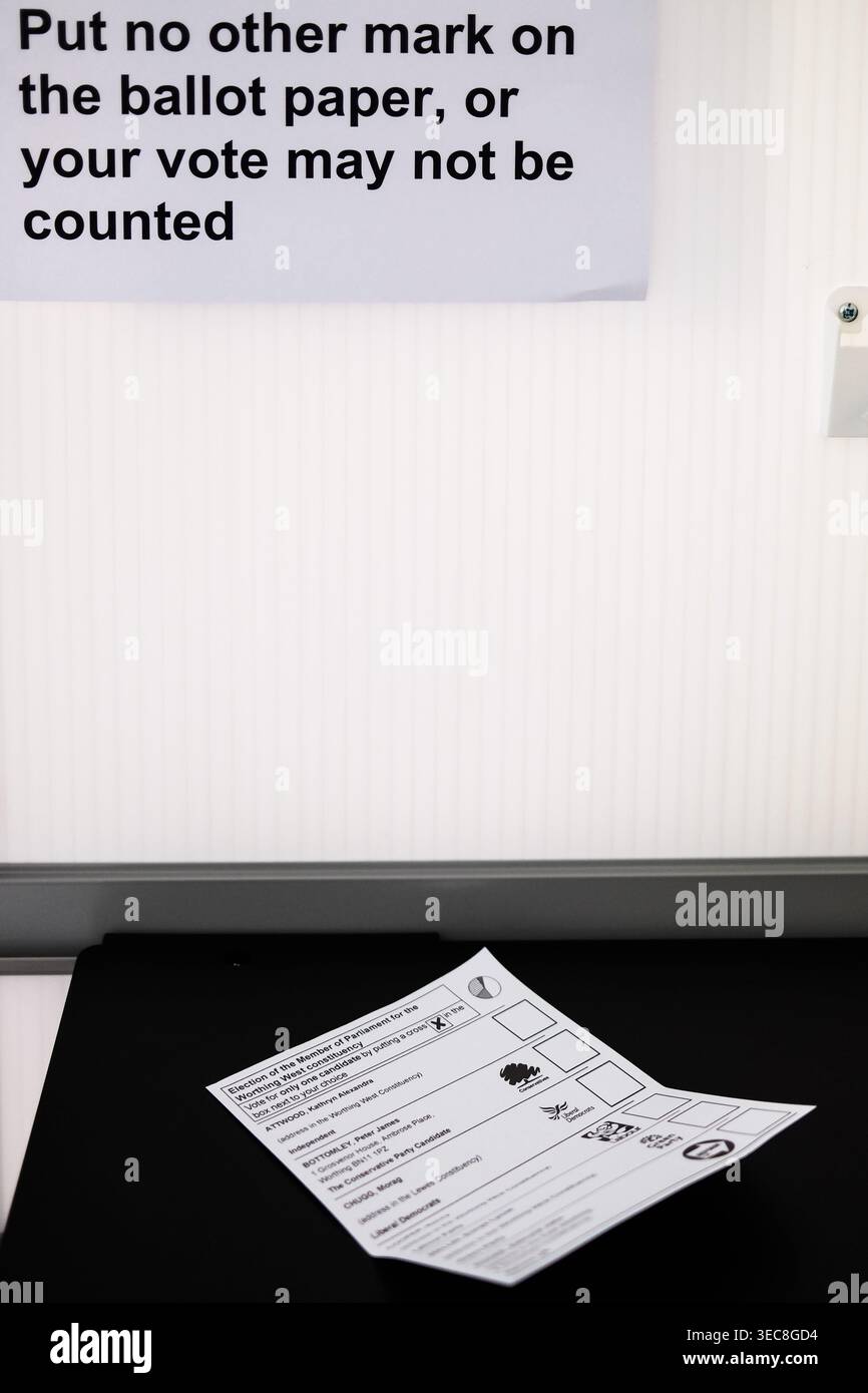 Dettaglio di una scheda elettorale e di un cartello con le istruzioni ufficiali all'interno di un seggio elettorale nel Regno Unito durante le elezioni, che avverte gli elettori di non lasciare alcun altro segno o segno Foto Stock