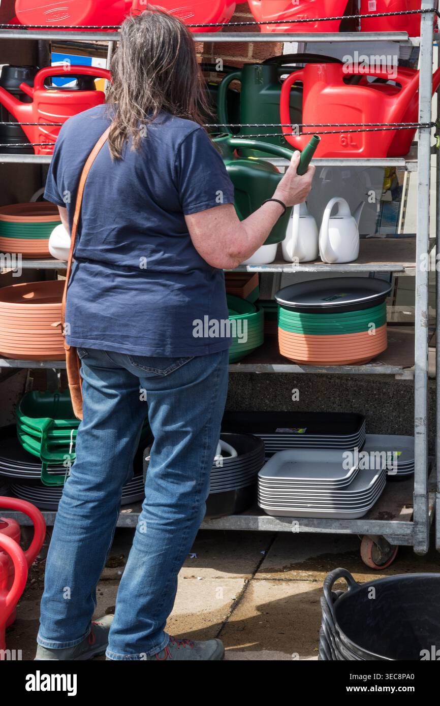 Donna che sceglie un annaffiatoio in plastica da un negozio di ferramenta. Foto Stock