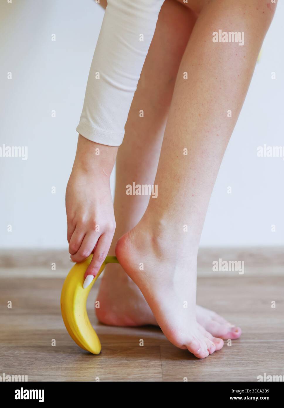 Primo piano di un passo scaldo sulla buccia di banana, pericolo comico, perdita di equilibrio e incidente domestico inaspettato. Foto Stock