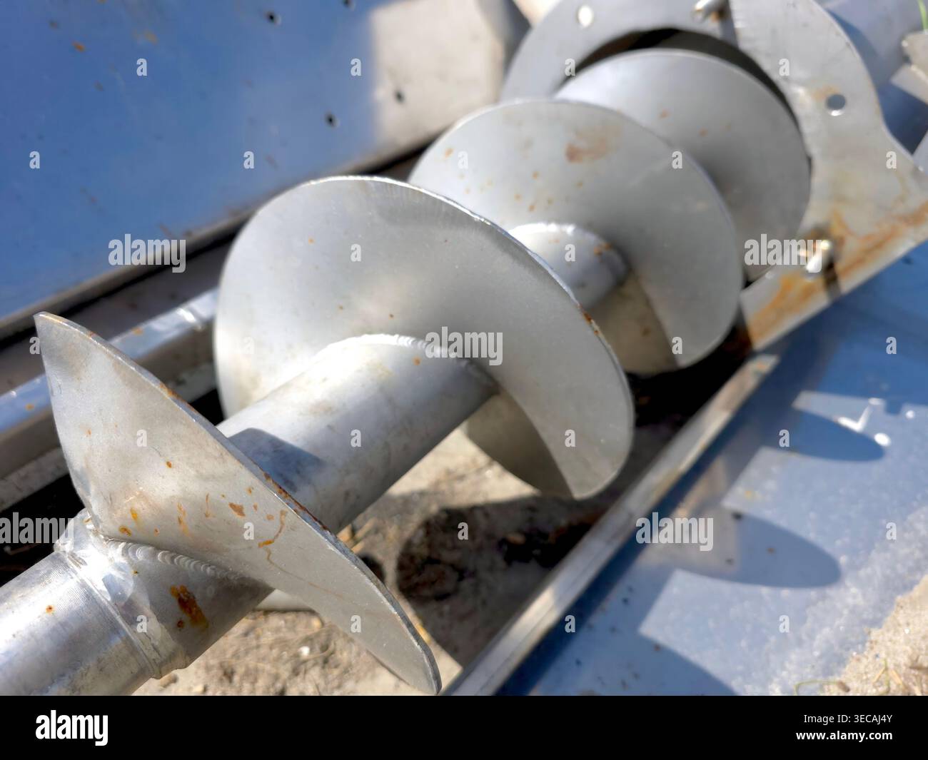 Un trasportatore a vite a spirale è posizionato in un cantiere edile. Aiuta a movimentare in modo efficiente i materiali sfusi. I lavoratori lo utilizzano spesso per varie attività. Foto Stock