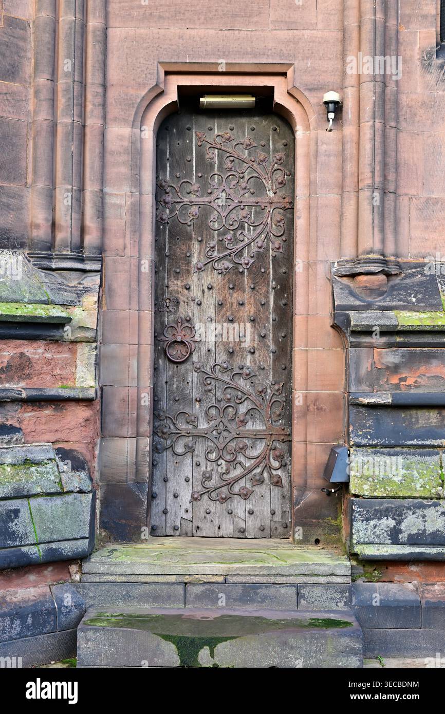 Porta in legno medievale decorata con cerniere in ferro battuto in pareti di arenaria Foto Stock
