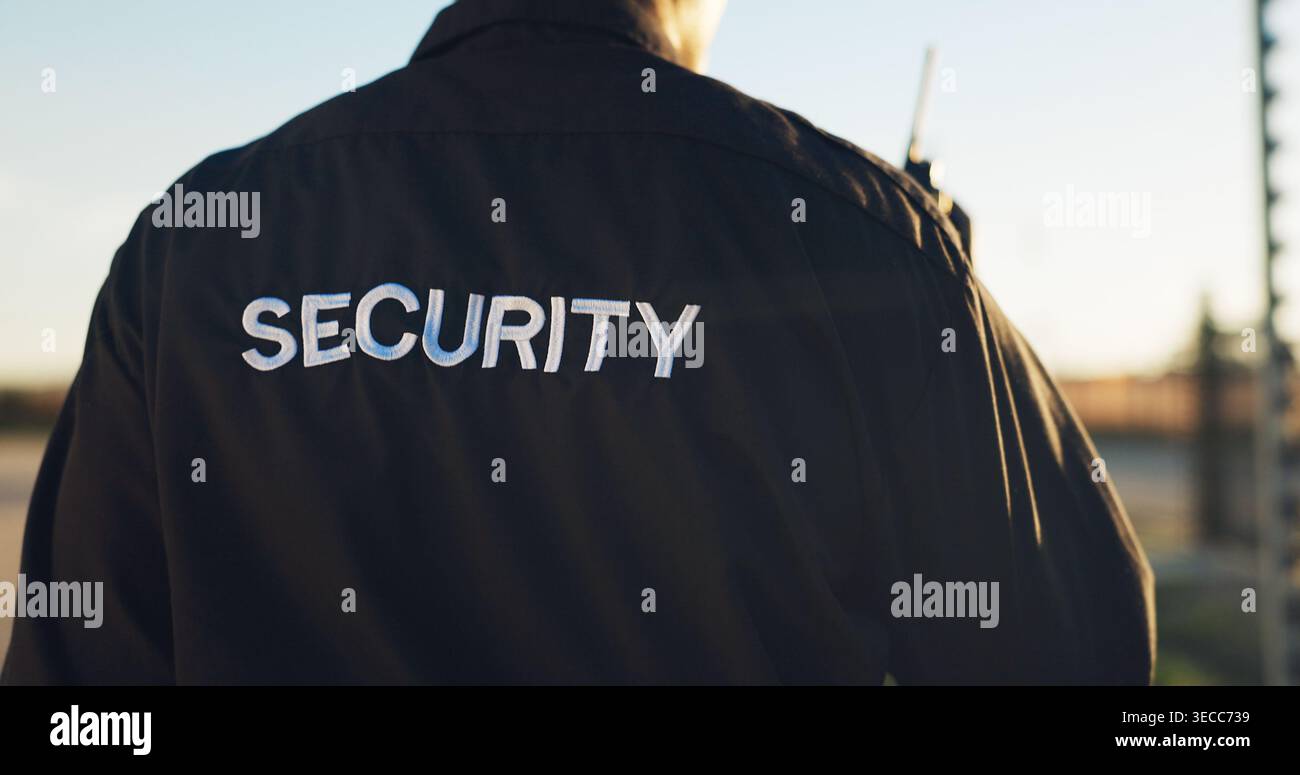 Schiena, guardia e sicurezza con uniforme all'aperto per la sorveglianza, l'autorità e la protezione perimetrale. Servizi di persona maschile, radio e guardia del corpo per Foto Stock
