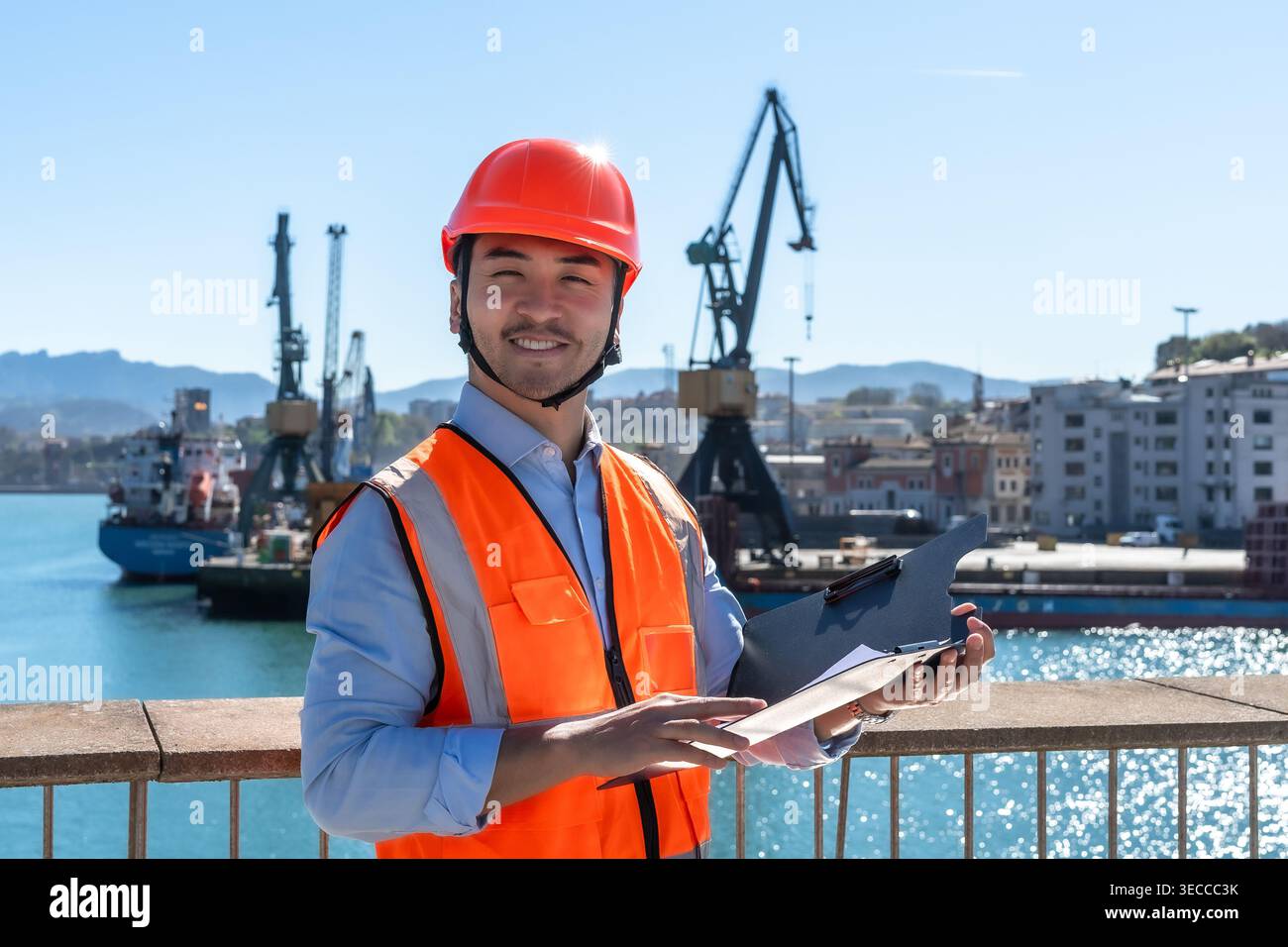 Lavoratore portuale asiatico che sovrintende alle operazioni di carico Foto Stock