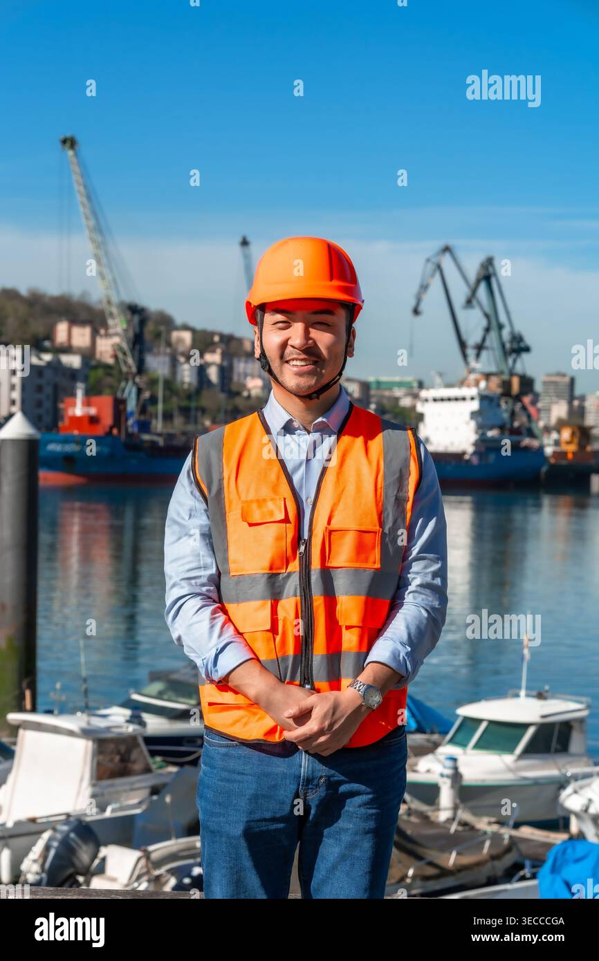 Il cargo asiatico che sorride indossando il giubbotto di sicurezza Foto Stock