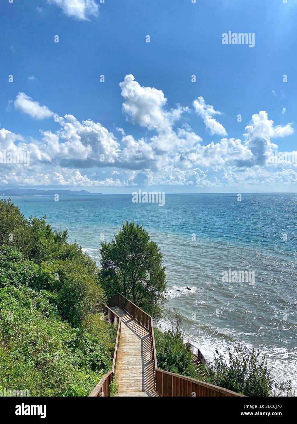 Scale in legno che conducono alla costa del mare, al cielo blu, al sole, al paesaggio panoramico - Immagine stock catturata con smartphone