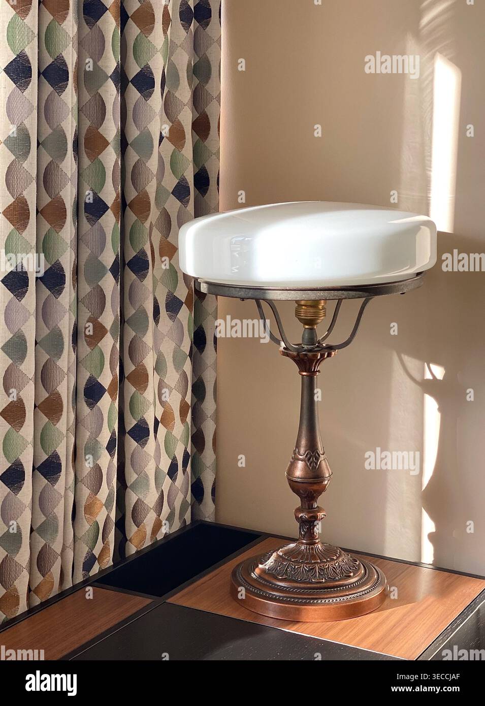 Lampada da tavolo vintage con luce solare calda e tende a motivi geometrici, interni accoglienti con ombre tenui e un'estetica retrò Foto Stock