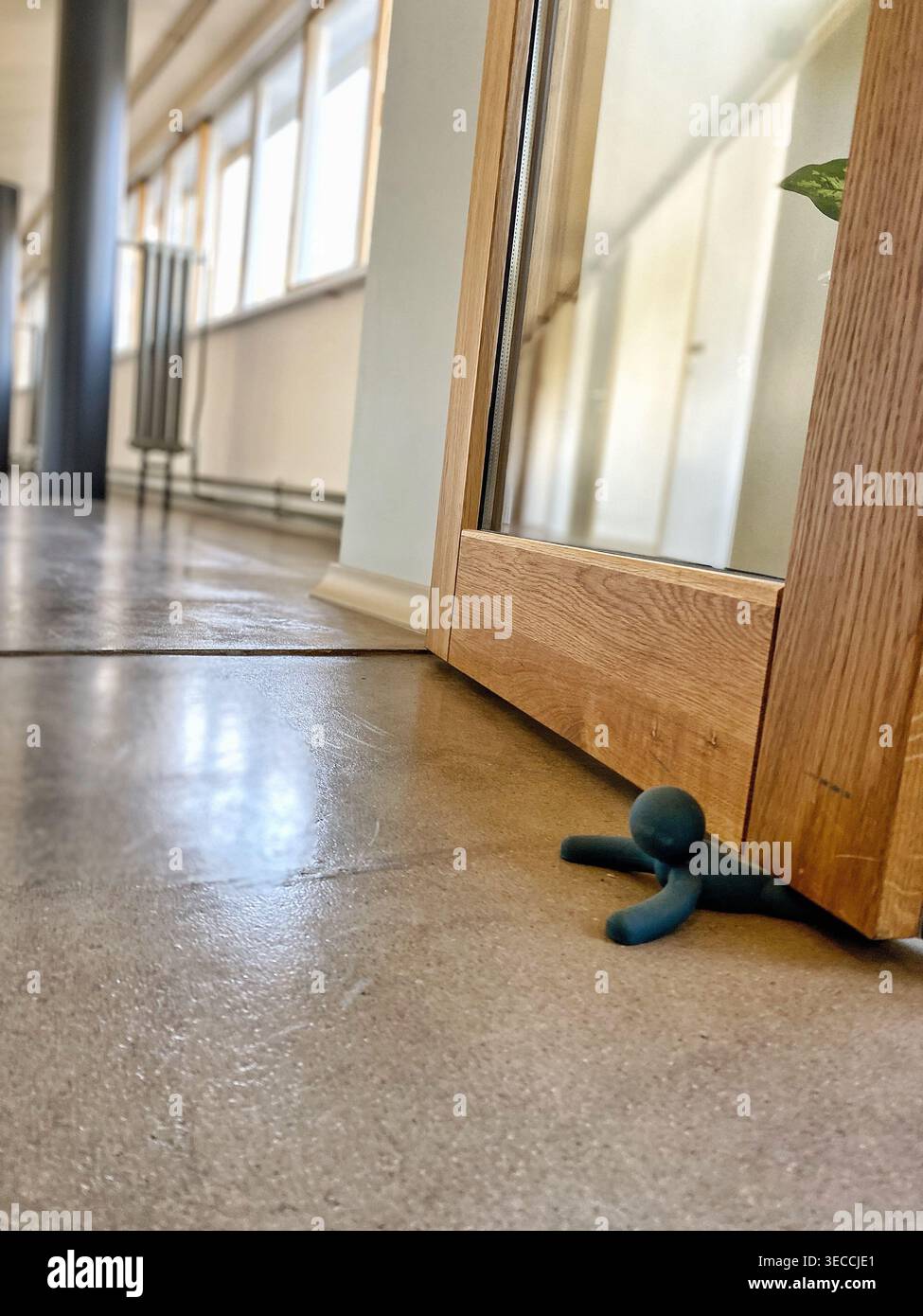 Piccola statuetta bloccata sotto una porta che simboleggia lo stress, la pressione e il burnout nella vita moderna Foto Stock