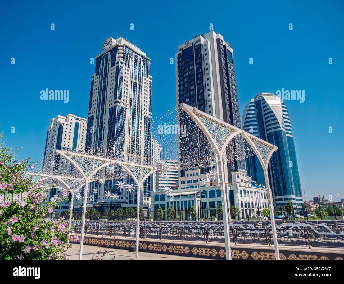Grozny, Russia - 30 luglio 2021: Moderni grattacieli e archi decorativi sono allineati al paesaggio urbano di Grozny sotto un cielo blu brillante Foto Stock