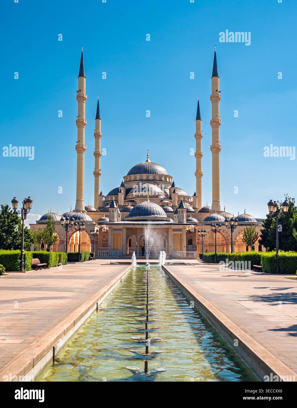 Grozny, Russia - 30 luglio 2021: La maestosa moschea Akhmad Kadyrov e la sua piscina riflettente sotto un cielo azzurro Foto Stock