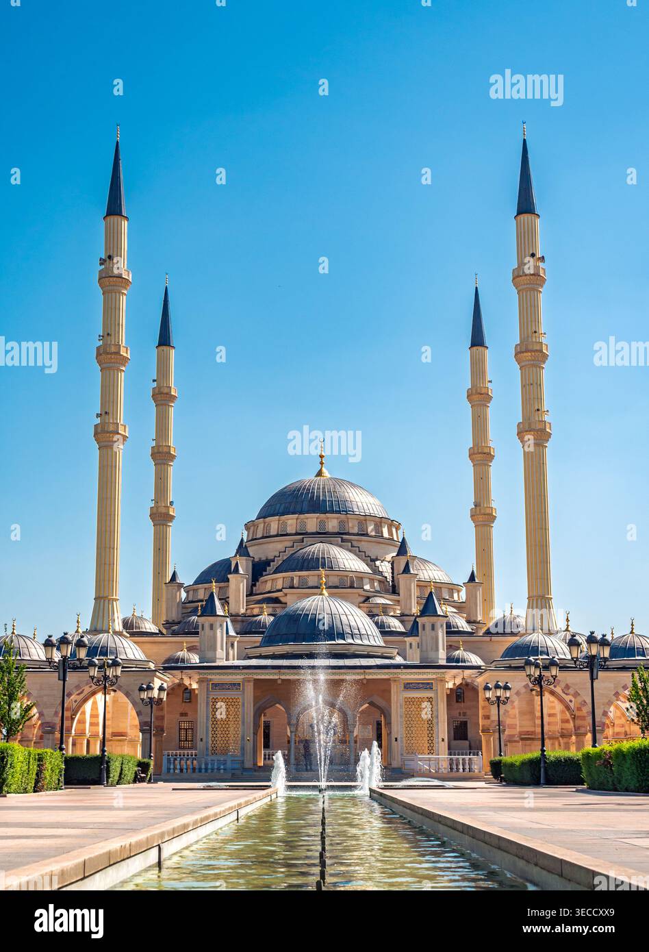 Grozny, Russia - 30 luglio 2021: La maestosa moschea Akhmad Kadyrov e la sua piscina riflettente sotto un cielo azzurro Foto Stock