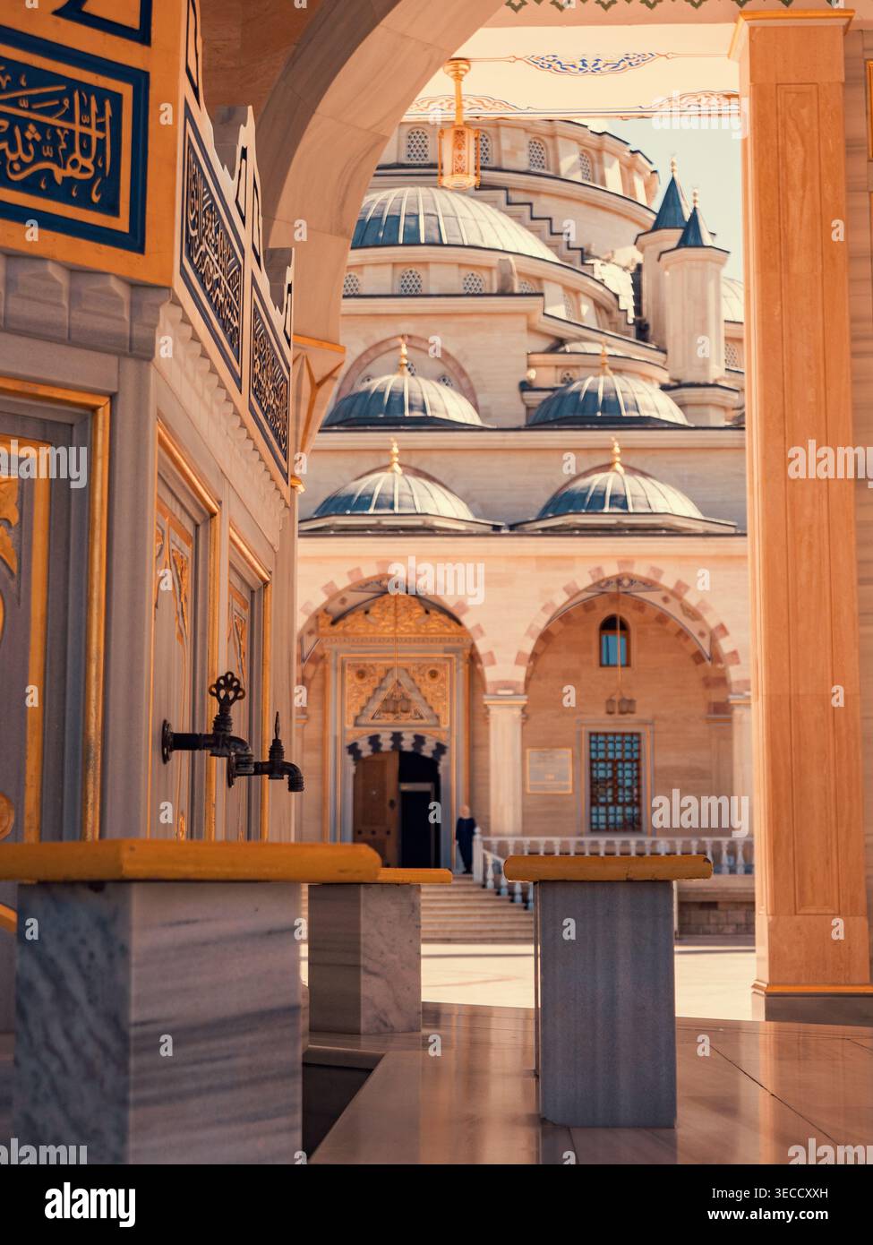 Grozny, Russia - 30 luglio 2021: Il cuore della moschea cecena attraverso un ingresso ad arco, che rivela grandi cupole e strutture di abluizione in marmo Foto Stock
