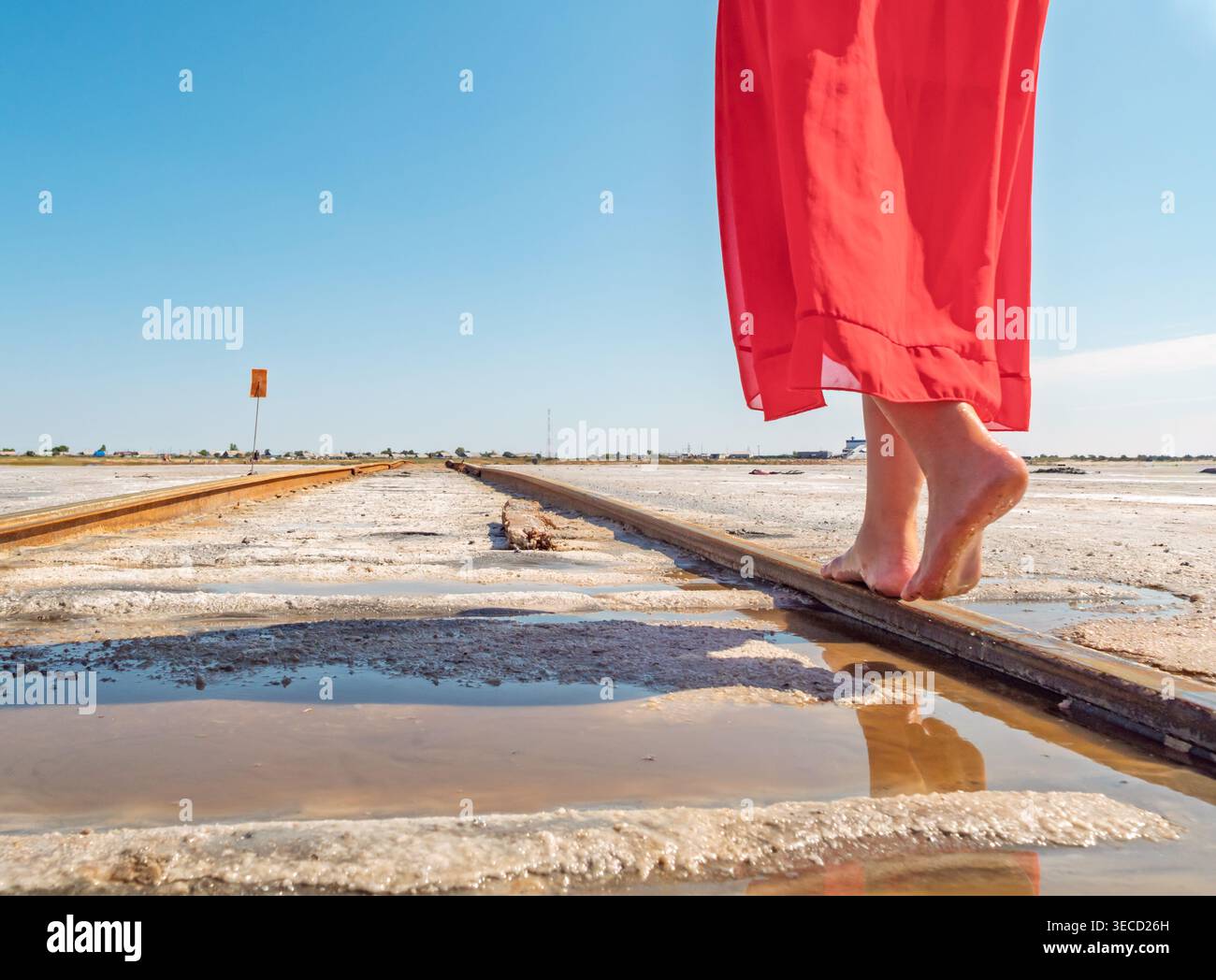 Scalini a piedi nudi sui binari della ferrovia salina del lago Bursol sotto un cielo blu brillante Foto Stock