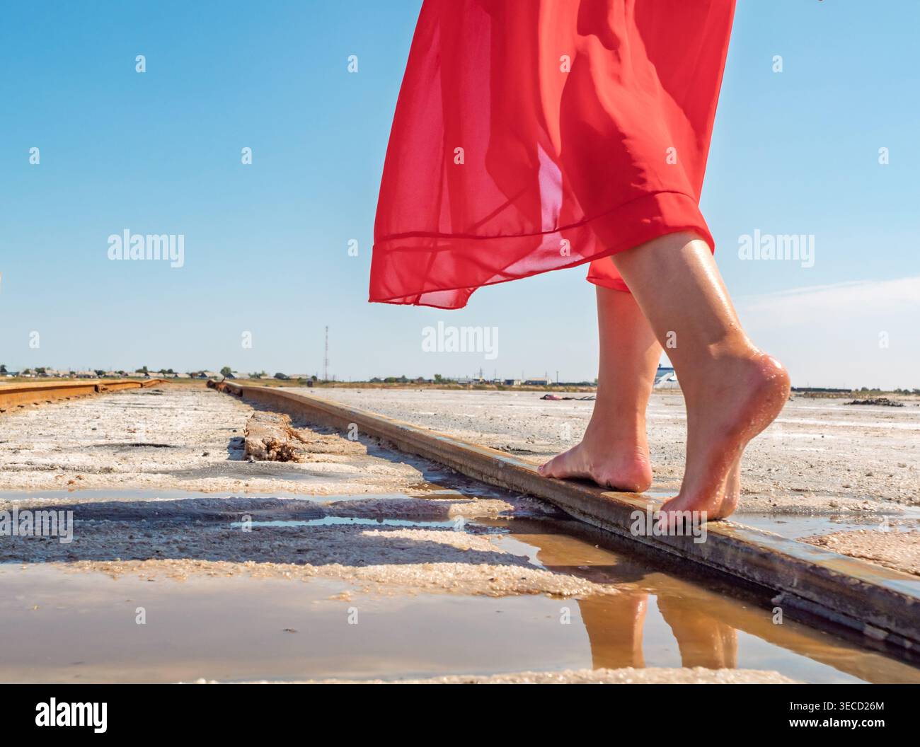 Scalini a piedi nudi sui binari della ferrovia salina del lago Bursol sotto un cielo blu brillante Foto Stock
