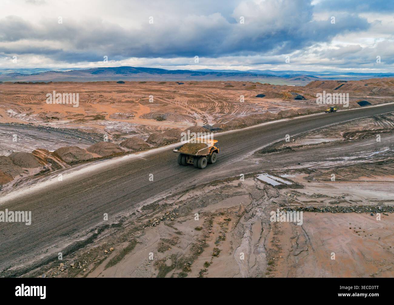 La vista aerea mostra un grande dumper che trasporta materiali su un'ampia strada sterrata in una miniera a cielo aperto durante il giorno Foto Stock