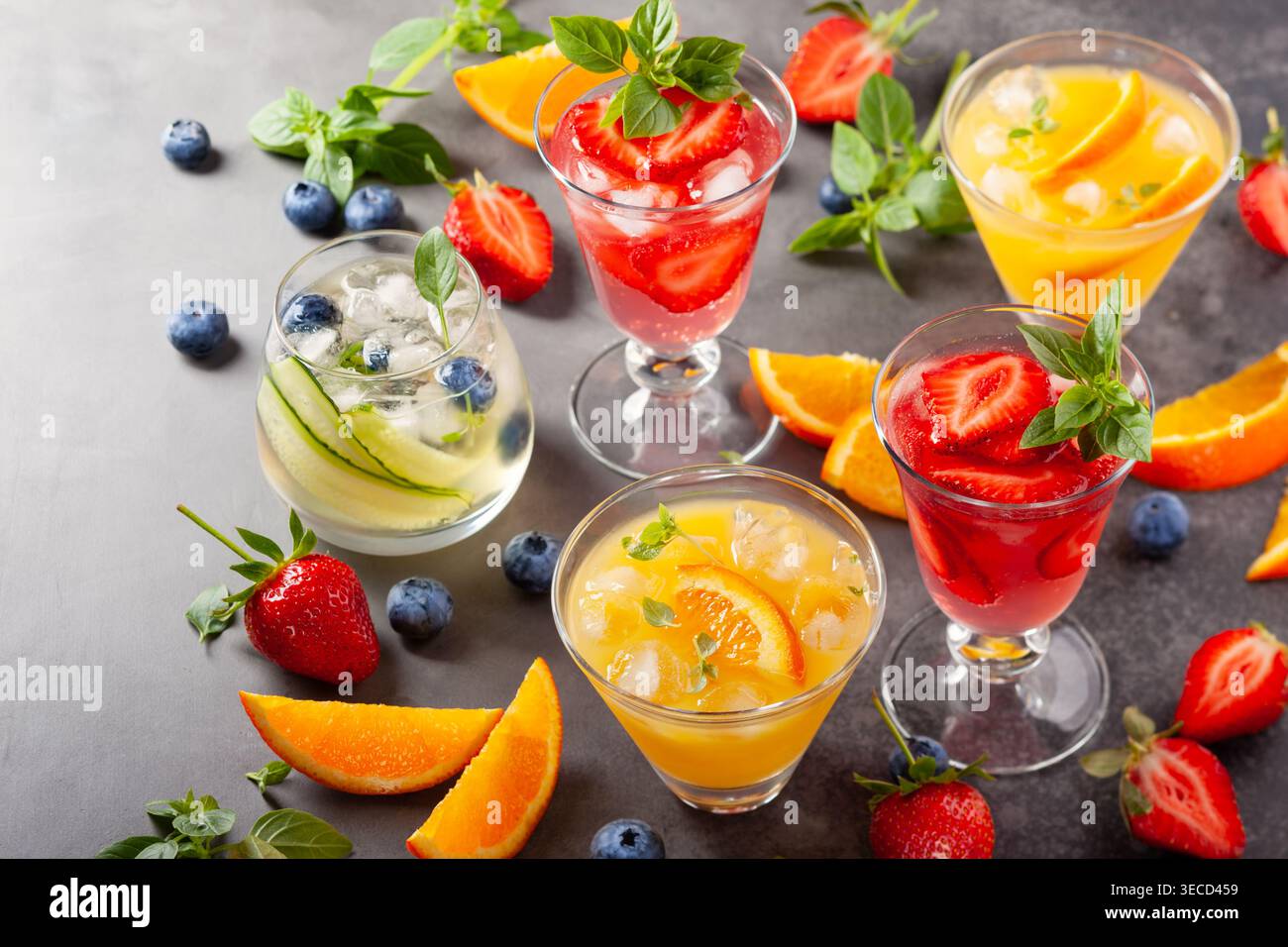 Assortimento di cocktail analcolici estivi con bacche fresche, erbe e frutta su sfondo scuro. Foto Stock