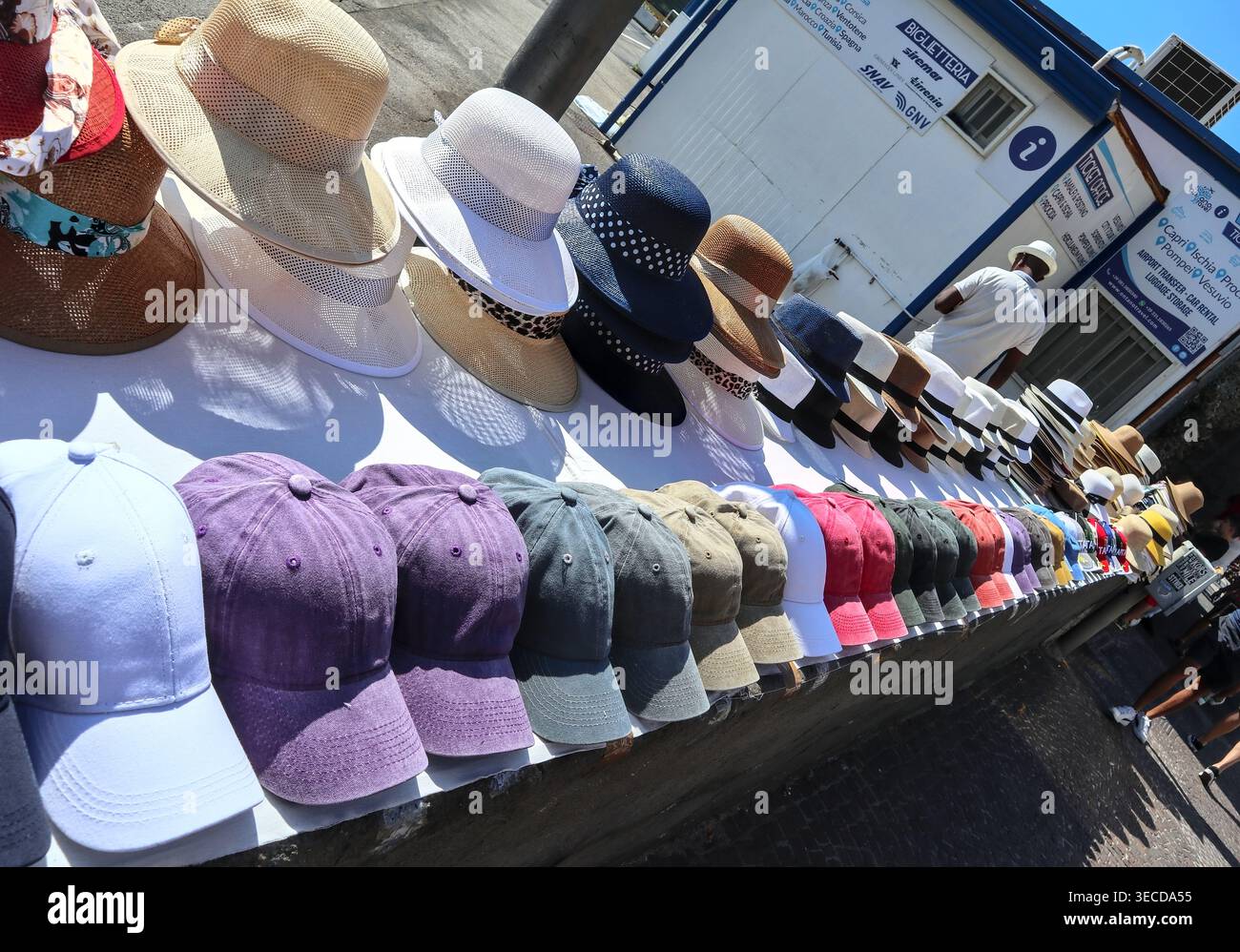 Cappelli e cappellini in vendita presso una biglietteria di souvenir vicino alla biglietteria del traghetto a Napoli, Italia. - Cappelli in vendita in un banco di souvenir Foto Stock