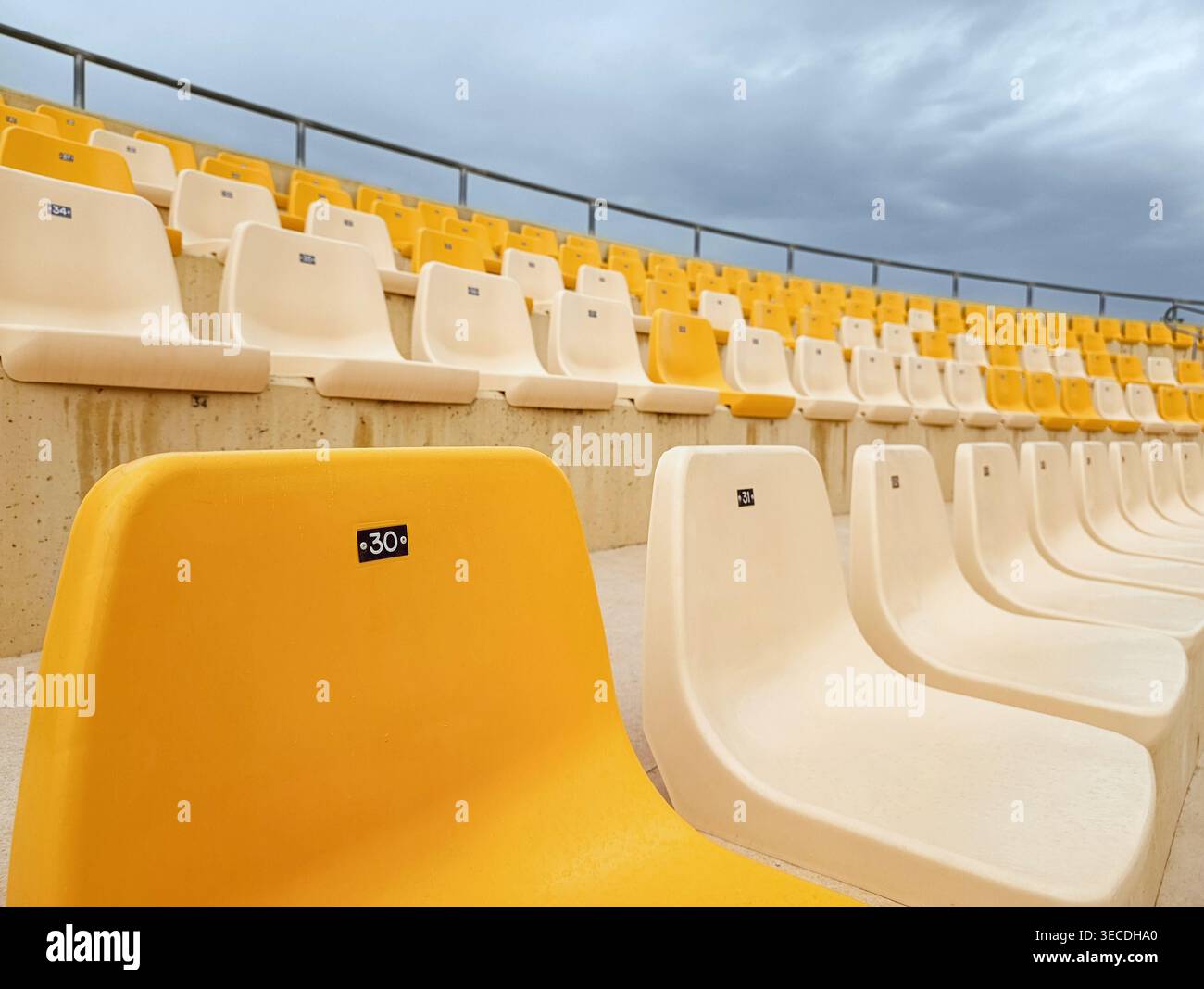 Yellow Stadium Seat in primo piano con file vuote dietro Foto Stock