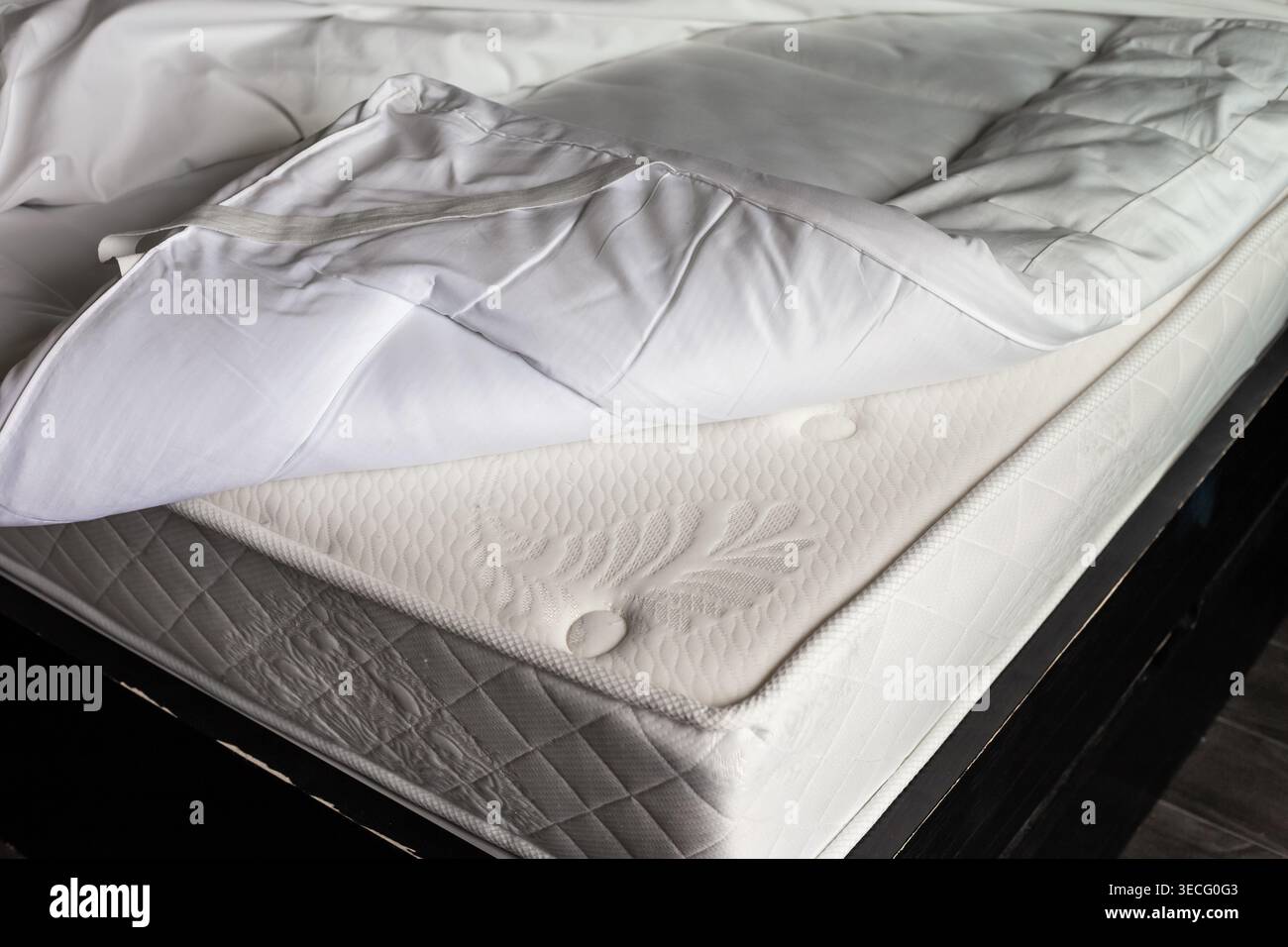 Un coprimaterasso trapuntato bianco è ripiegato sul materasso. Biancheria da letto, comfort di casa, protezione del materasso Foto Stock