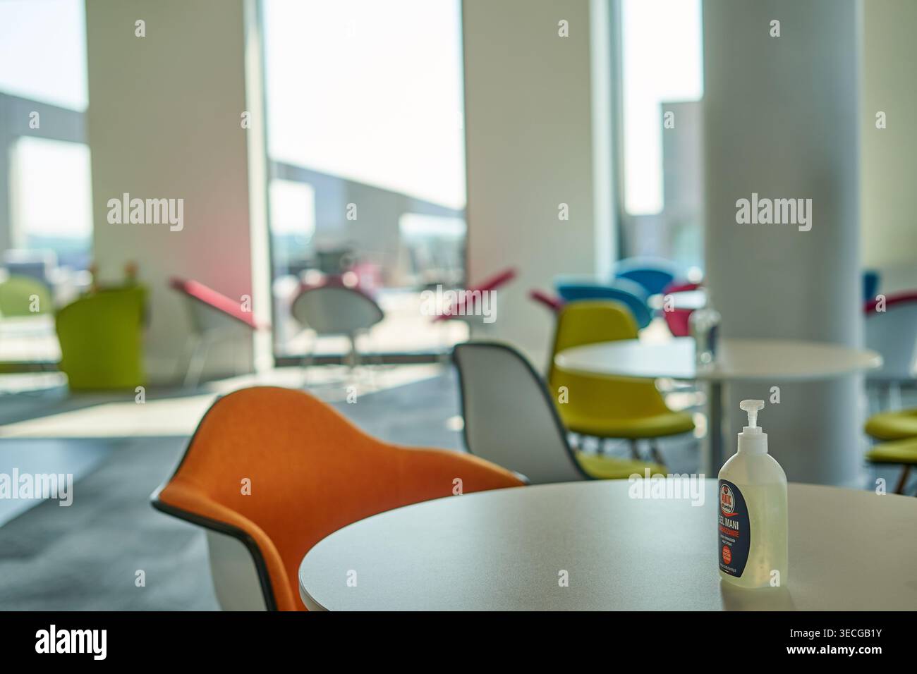 Interno moderno di ufficio o area relax aziendale con sedie contemporanee colorate in arancione, giallo, blu, rosso e grigio disposte intorno al bianco Foto Stock
