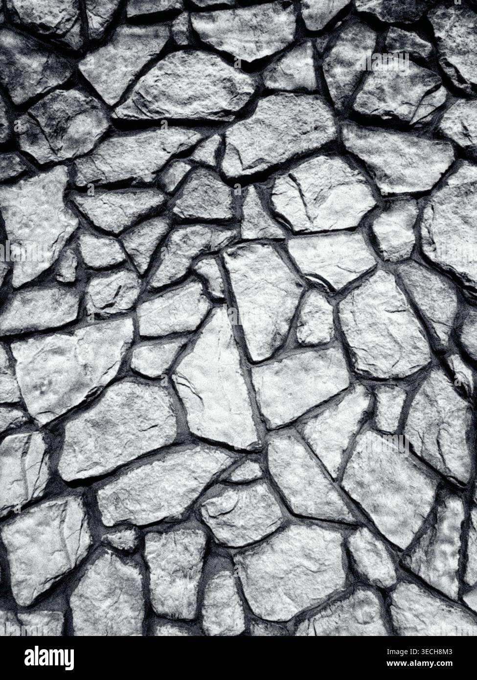 Struttura bianca e nera di un muro rustico in pietra con motivi irregolari di roccia e giunti in cemento Foto Stock