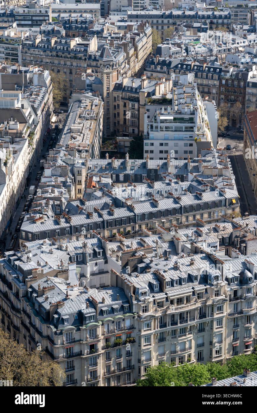 Blocco residenziale parigino visto dall'alto, con tetti e camini che si innalzano a diversi piani sopra le strette strade Foto Stock
