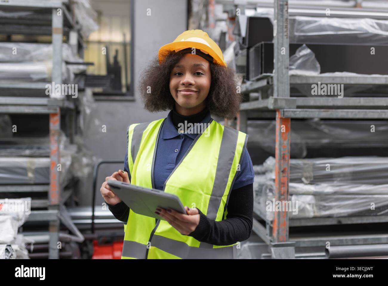 Lavoratrice donna in una fabbrica di prodotti metallici che fa l'inventario delle merci e controlla le scorte in un magazzino aperto utilizzando un tablet digitale. Foto Stock