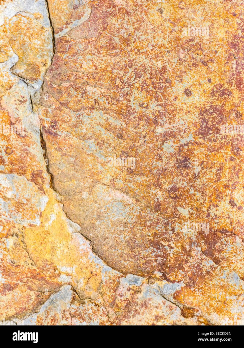 Primo piano di una superficie in pietra intemprata con tonalità di arancio arrugginito e minerali beige, linee naturali di crepe e texture astratta a chiazze, ideale per lo sfondo Foto Stock