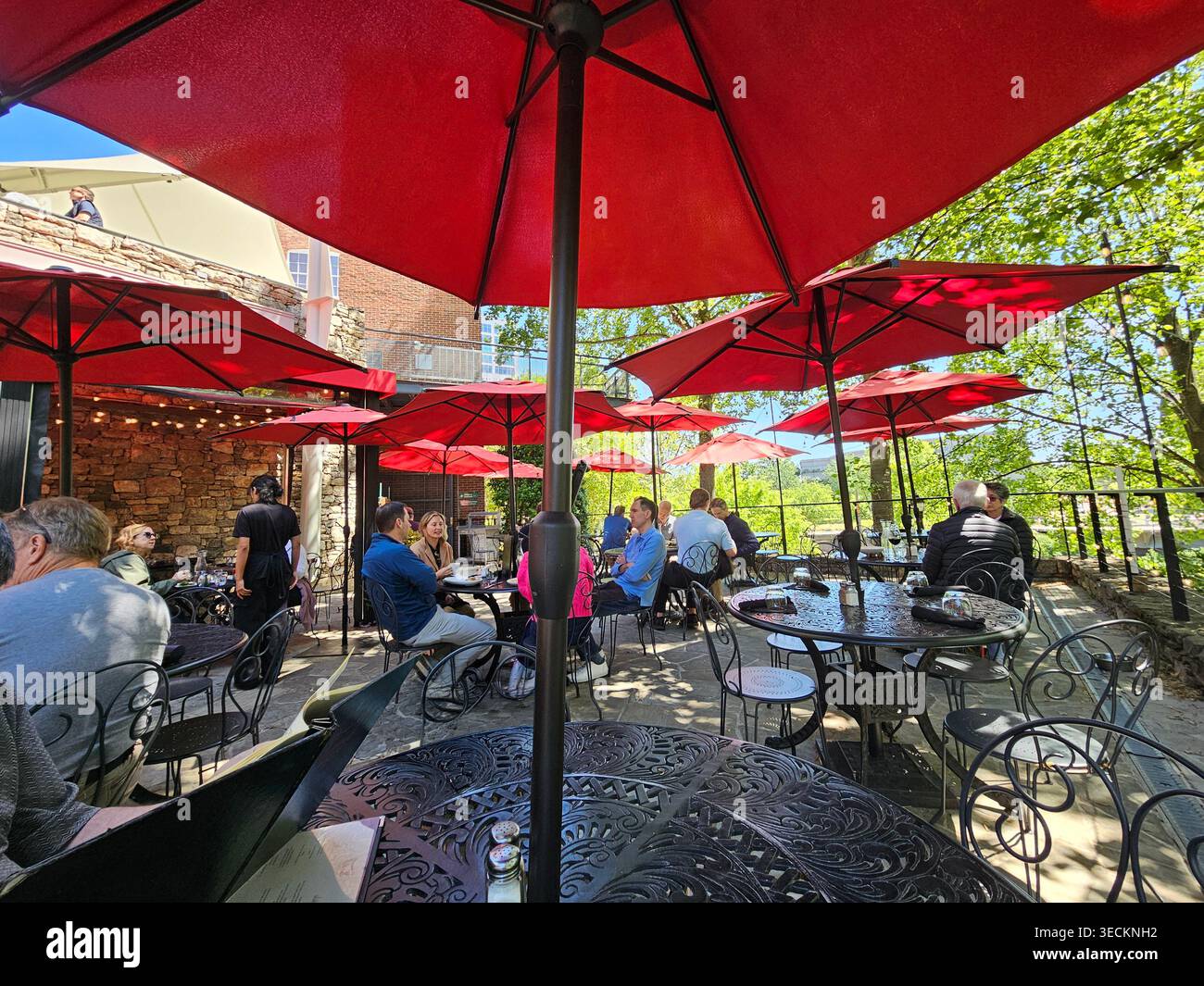 Passerelle, Falls Park sulla Reedy, Greenville, South Carolina. Un tradizionale bistrot francese con vista sul parco. Gli ombrelli rossi assicurano un posto ombreggiato Foto Stock