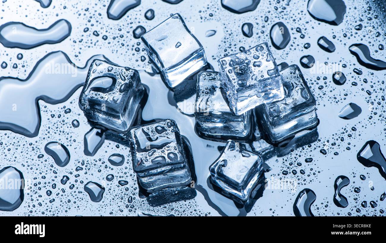 I cubetti di ghiaccio si fondono formando gocce d'acqua e condensa su una superficie blu riflettente Foto Stock