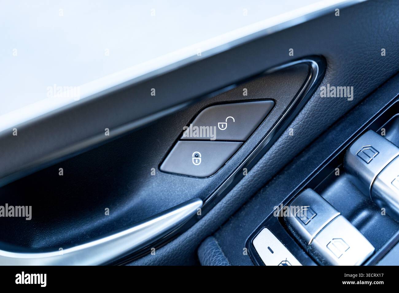 Primo piano dettagliato del pannello interno della portiera di un'auto moderna che mostra i pulsanti di bloccaggio e sbloccaggio e i comandi degli alzacristalli elettrici, evidenziando il design automobilistico e la sicurezza Foto Stock