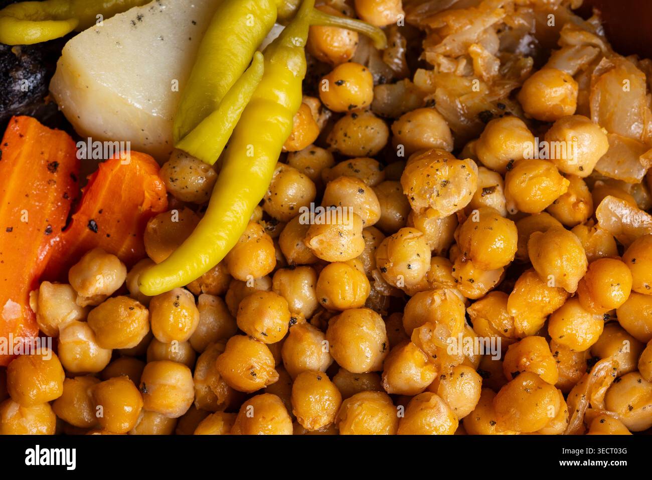 Primo piano del tradizionale cocido spagnolo con ceci teneri, carote vivaci, patate e peperoni saporiti. Una Mediterra sostanziosa e confortante Foto Stock