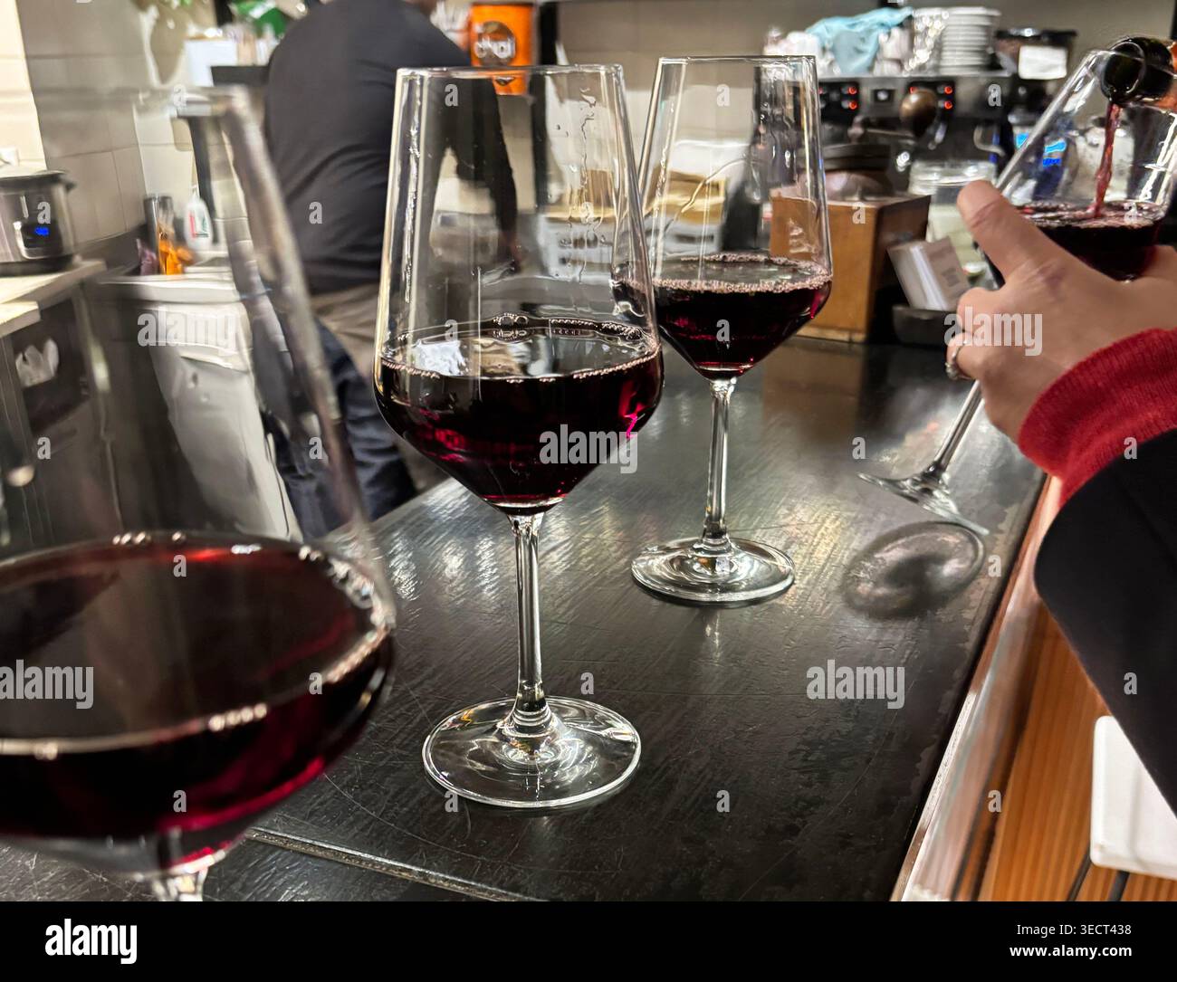Degustazione di vini rossi in bicchieri moderni al banco del bar scuro. Elegante atmosfera serale con sfondo sfocato bokeh. Stile di vita urbano, ospitalità. Foto Stock