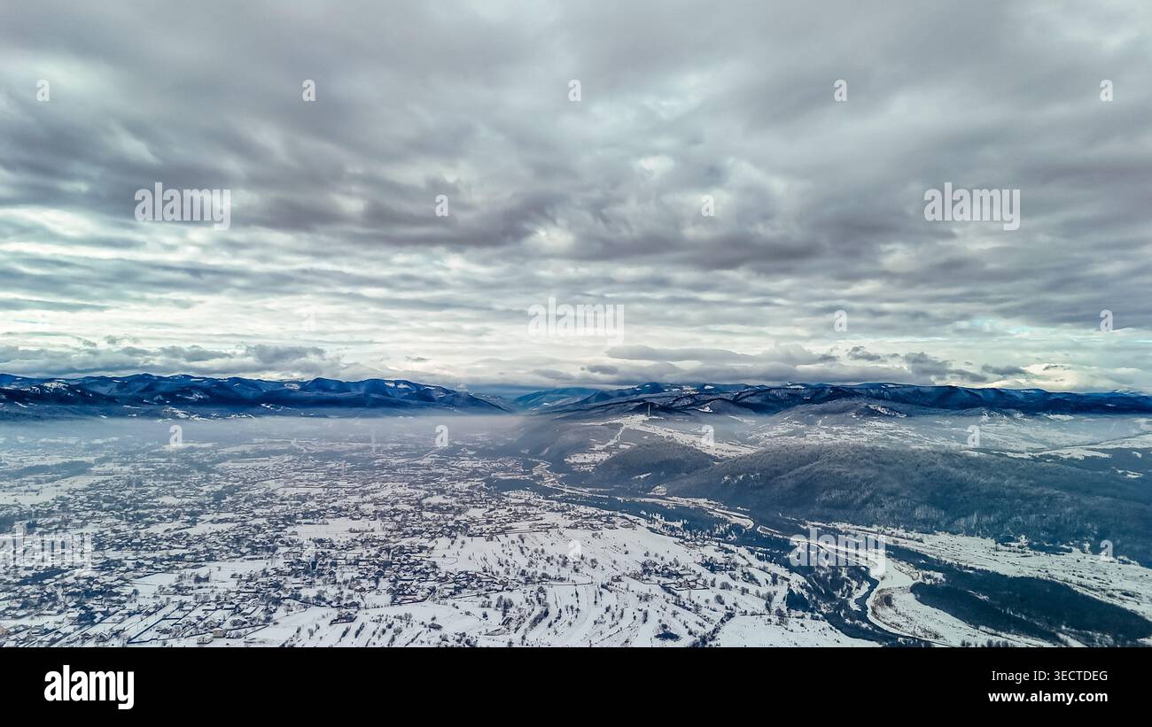 Un fiume tortuoso si intaglia attraverso creste innevate e foreste frastagliate in una vasta vista aerea. Le texture invernali e i canali ramificati rivelano la forma di nascosto Foto Stock