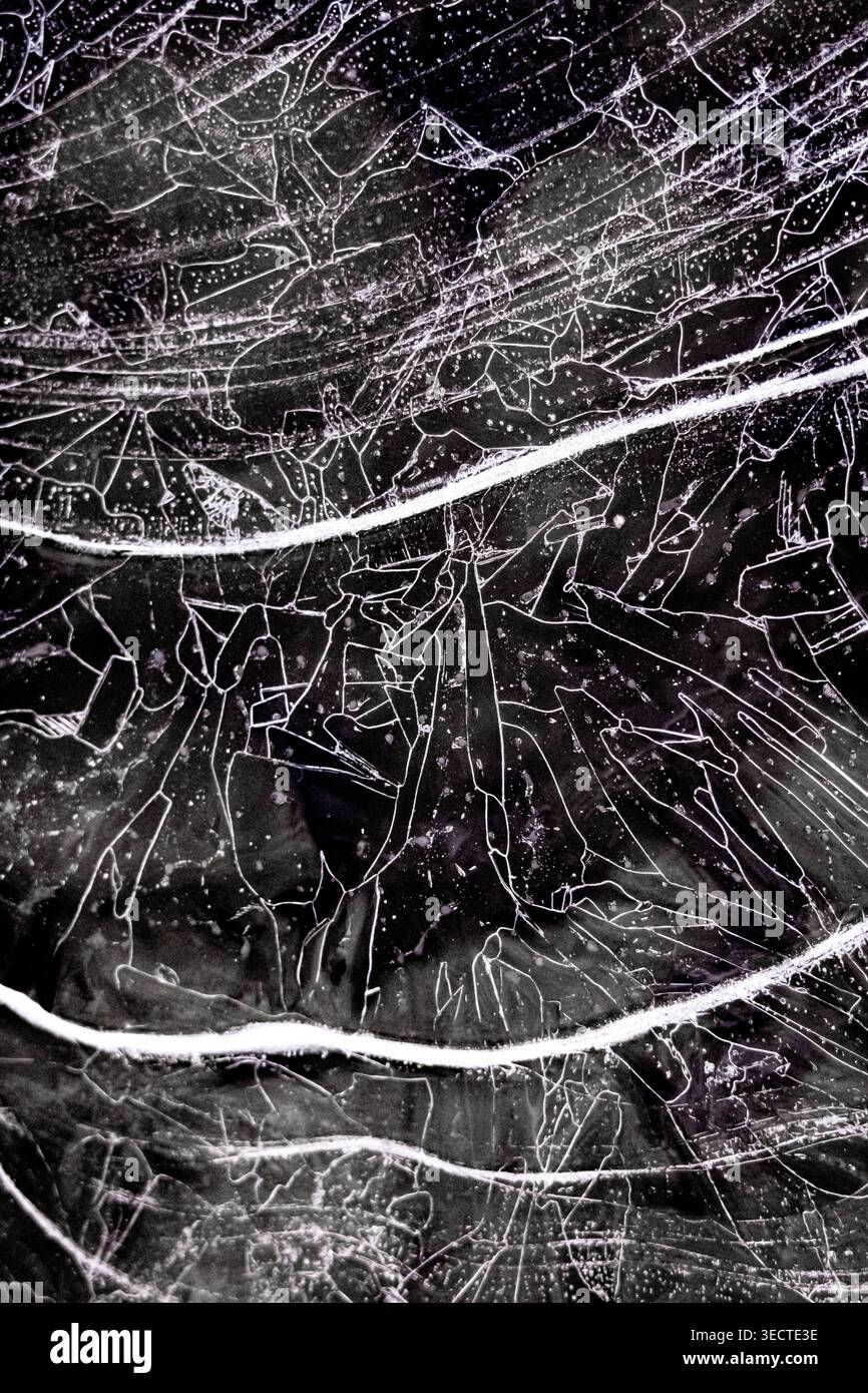 Vista grafica dall'alto del ghiaccio del lago incrinato con sottili linee bianche e bolle macchiate. Fratture interlacciate archi trasversali di sweep per formare un complesso Foto Stock