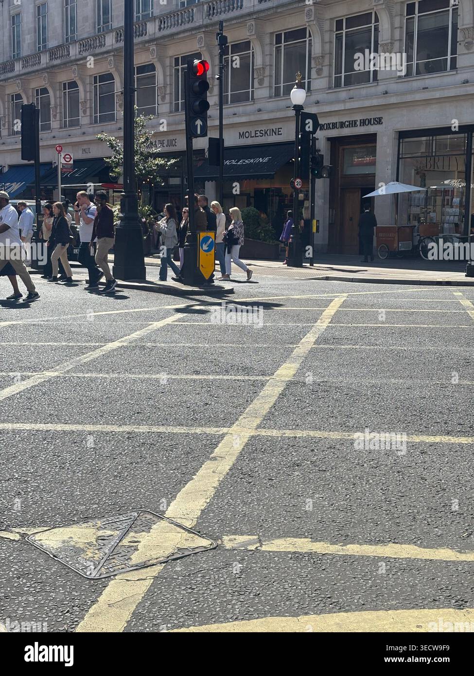 Pedoni che attraversano la strada da una juncion gialla su Regent Street, nel centro di Londra, Regno Unito, fuori da Roxburghe House e Moleskine Storefront - Immagine stock catturata con smartphone